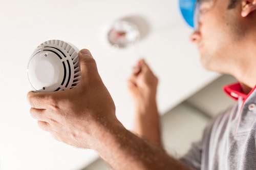 Technician quickly installing a cutting-edge smoke detector in a home to ramp up safety levels.