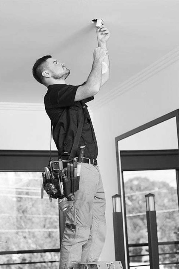 Certified electrician expertly installing an energy-efficient light fixture in a residential home.